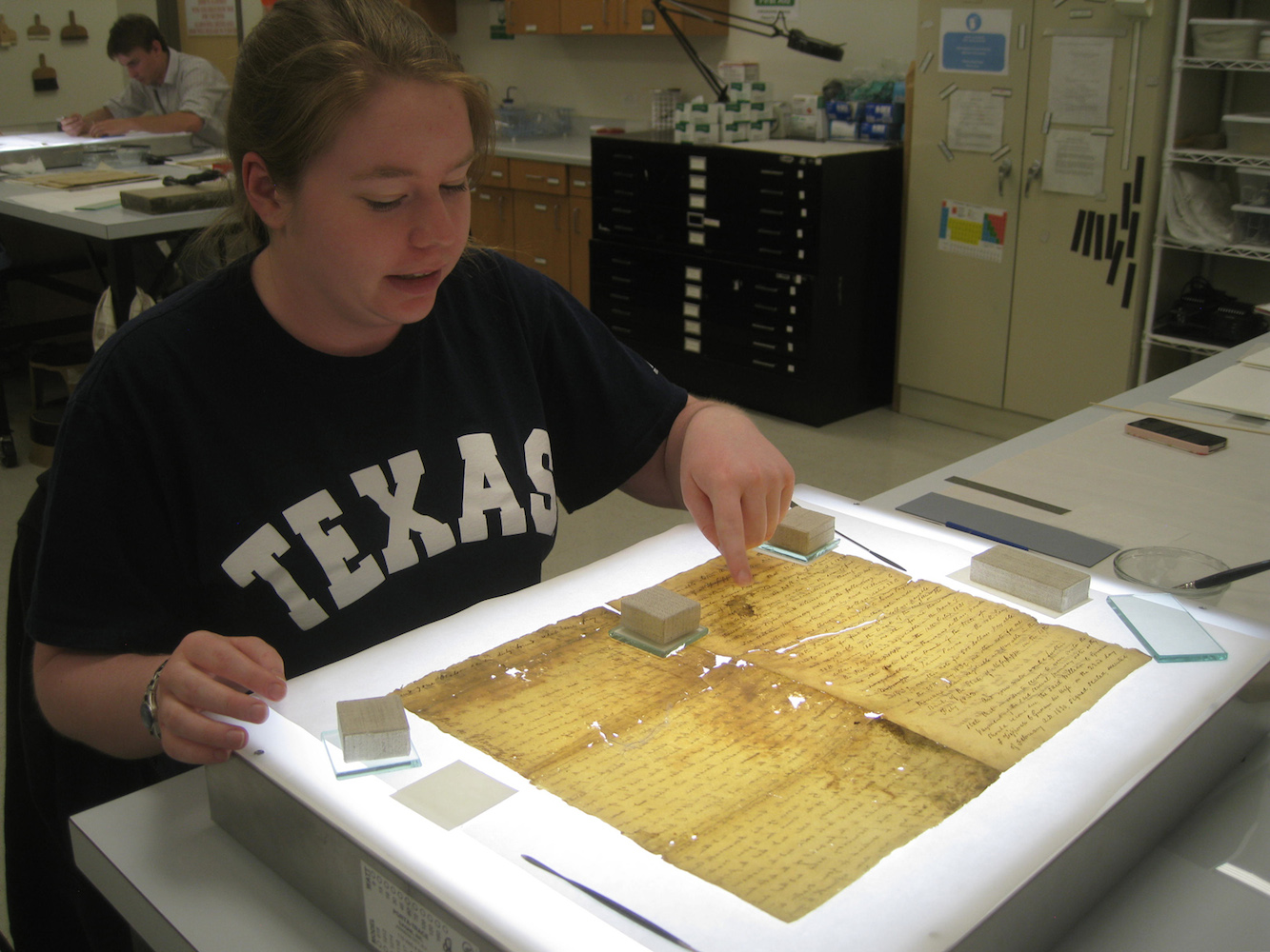 An archivist works at preserving an old text.