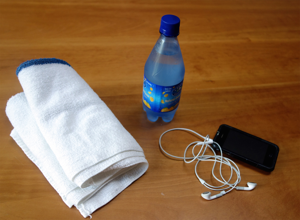 A hand towel, a music player with headphones, and a bottle of water.